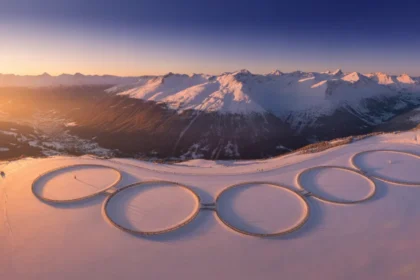 Vue aérienne d'une station de ski des Alpes françaises enneigée au lever du soleil, symbole de l'organisation des Jeux Olympiques d'hiver 2030 en France